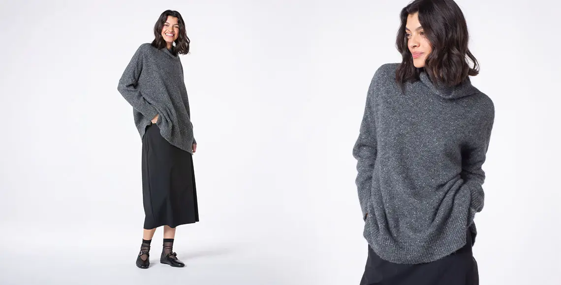 Woman smiling in a cozy gray sweater outfit.