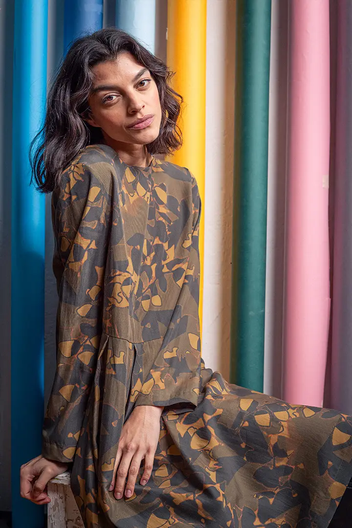 Woman in patterned dress against colorful backdrop