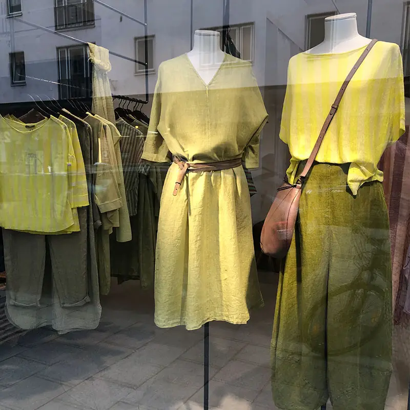 Etalage met stijlvolle groene en gele kleding.