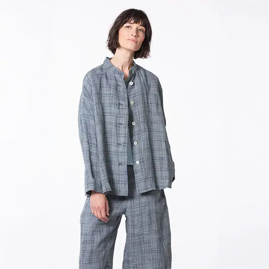 Woman in stylish gray plaid outfit, smiling.