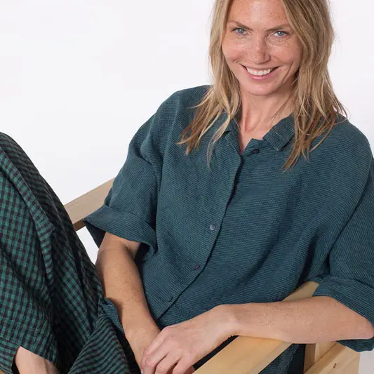 Smiling woman in green shirt, sitting comfortably.