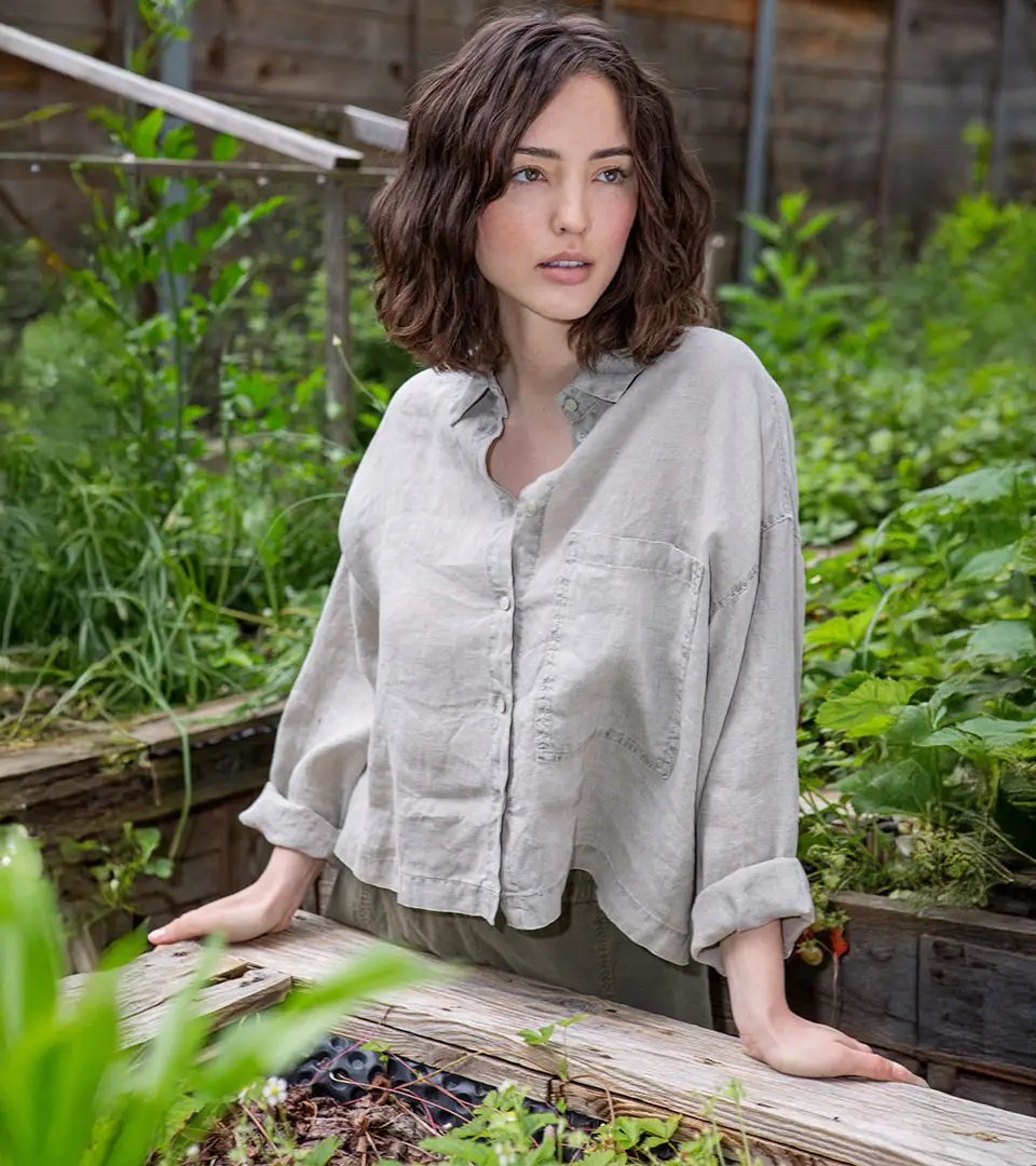 Young woman in garden, wearing a light shirt.