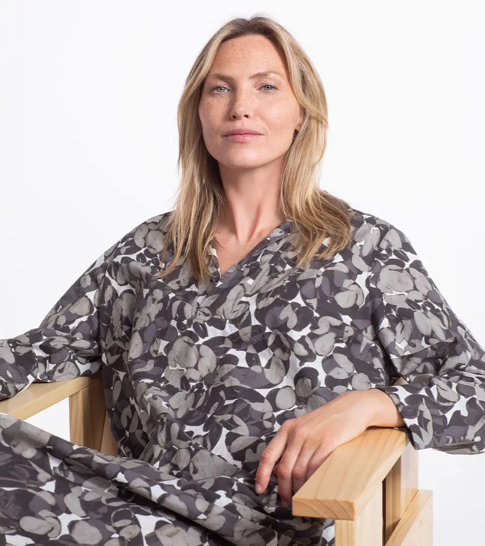 A woman sitting in a chair, wearing patterned attire.