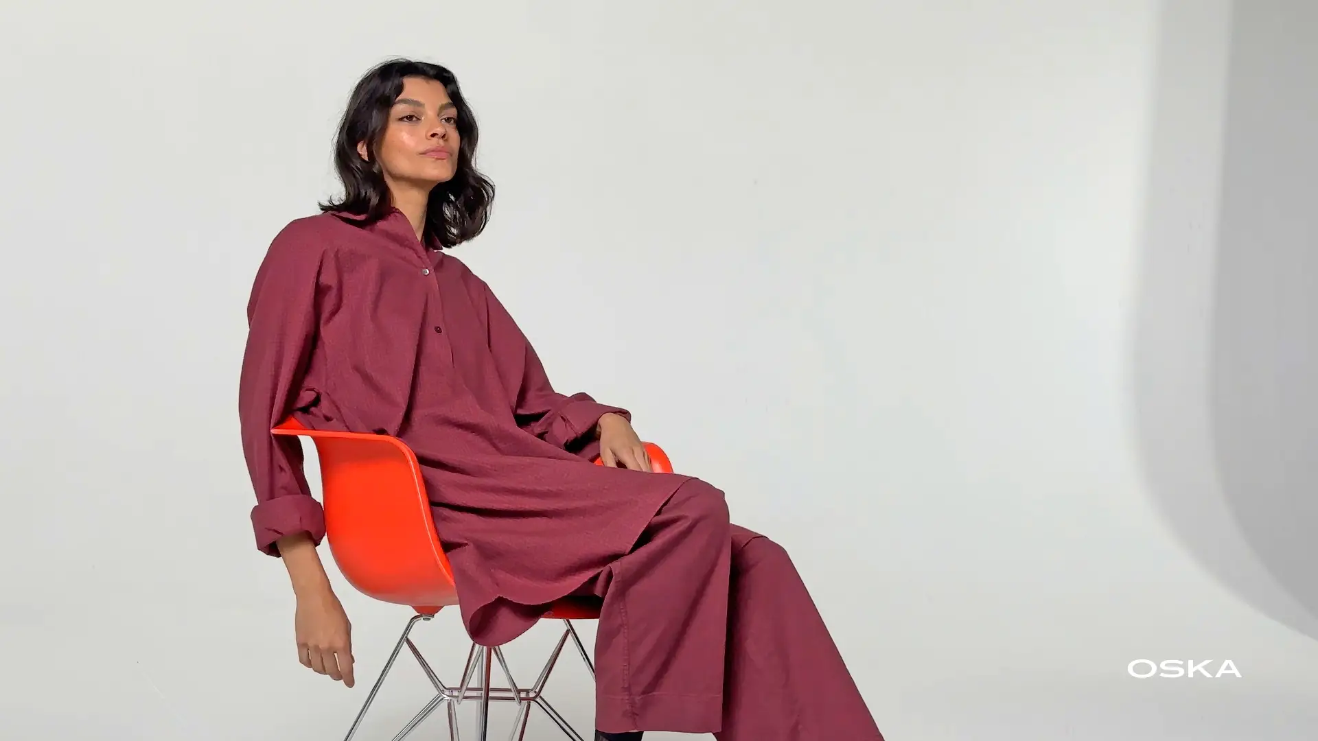 Model sitting in red outfit on orange chair