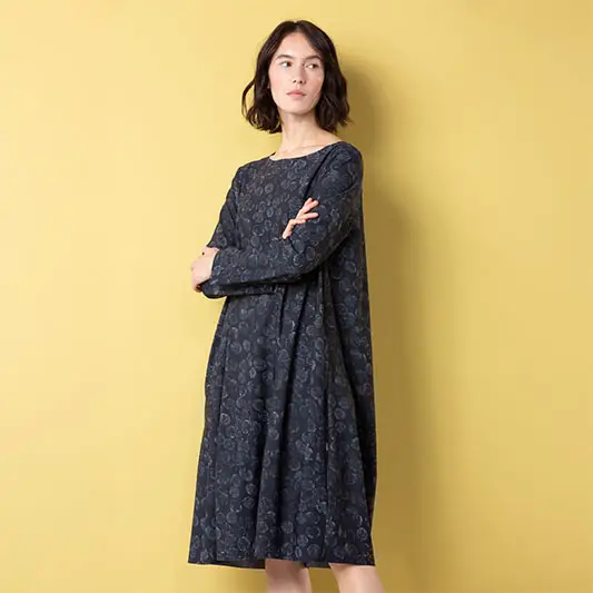 Model wearing a dark patterned dress against yellow background.