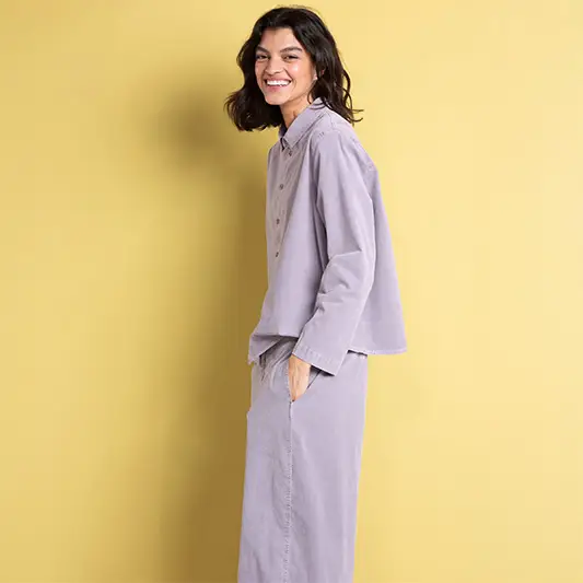Woman smiling in pastel outfit against yellow background.