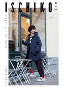 Model wearing cozy autumn jacket outside café.