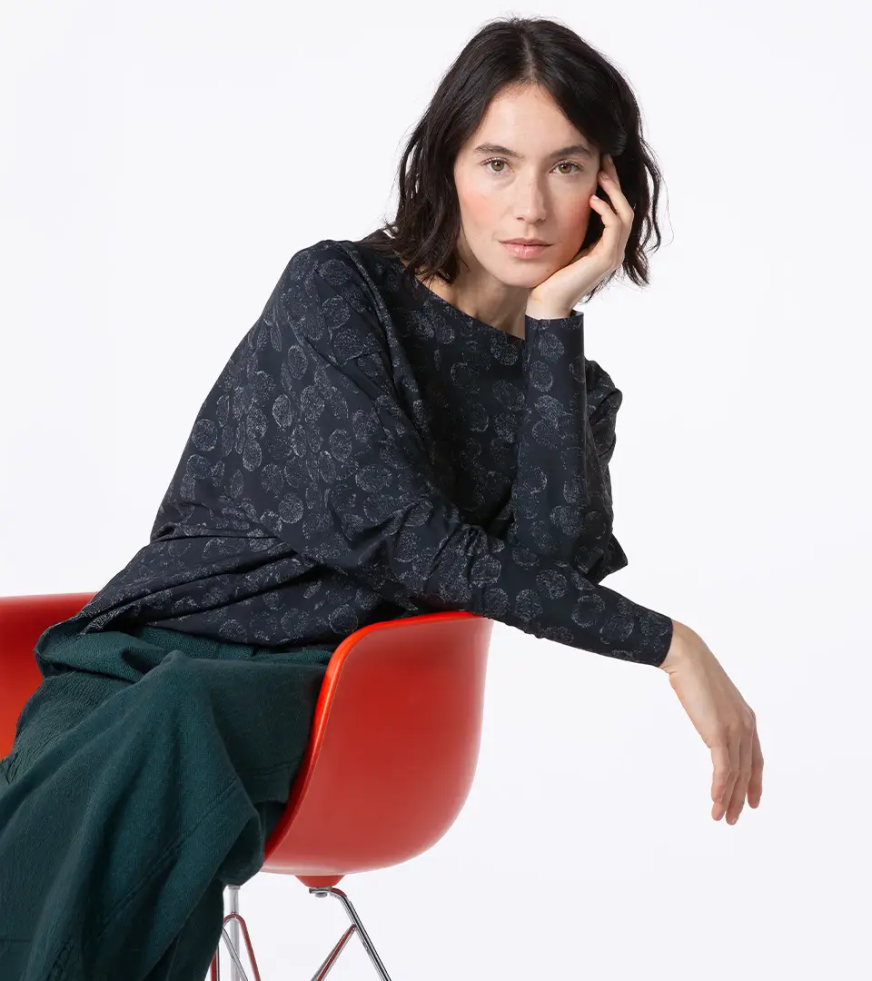 Model seated in a stylish black outfit.