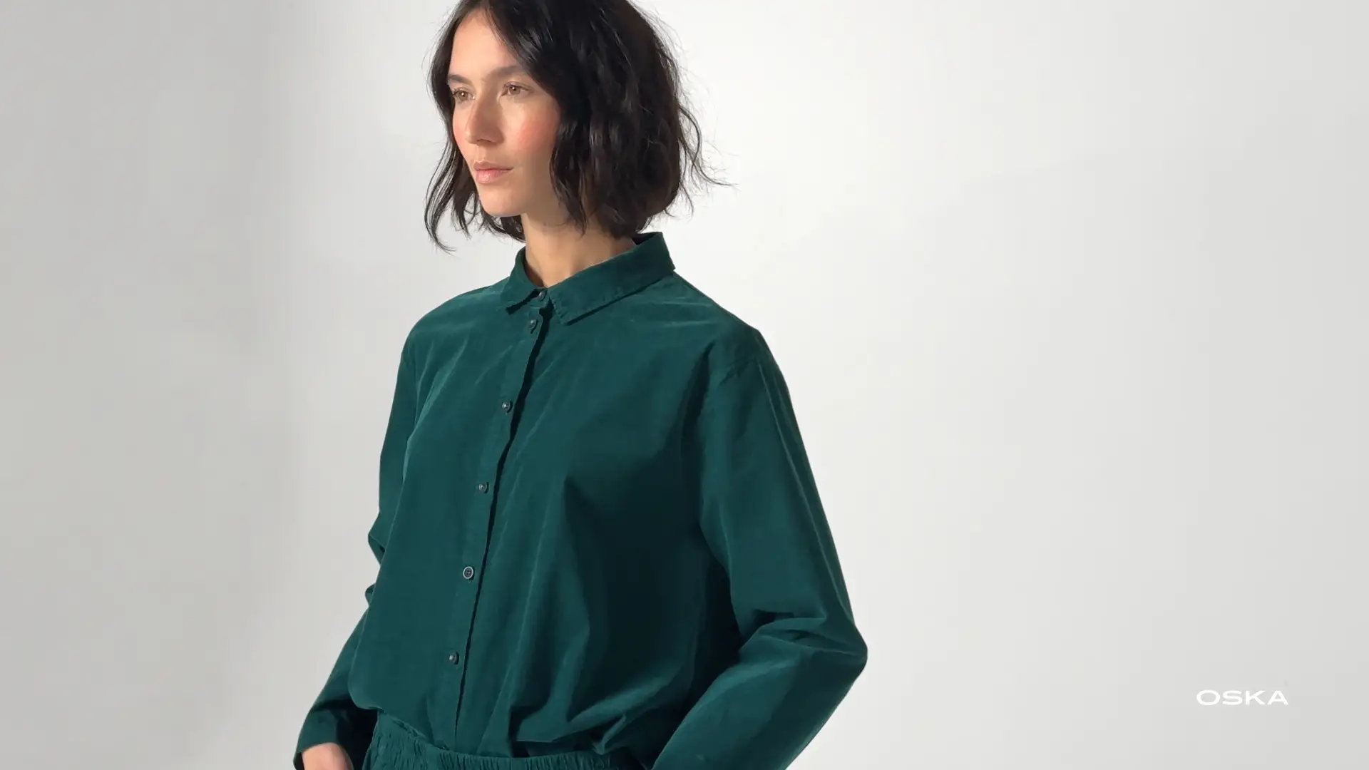 Woman wearing a teal button-up shirt.