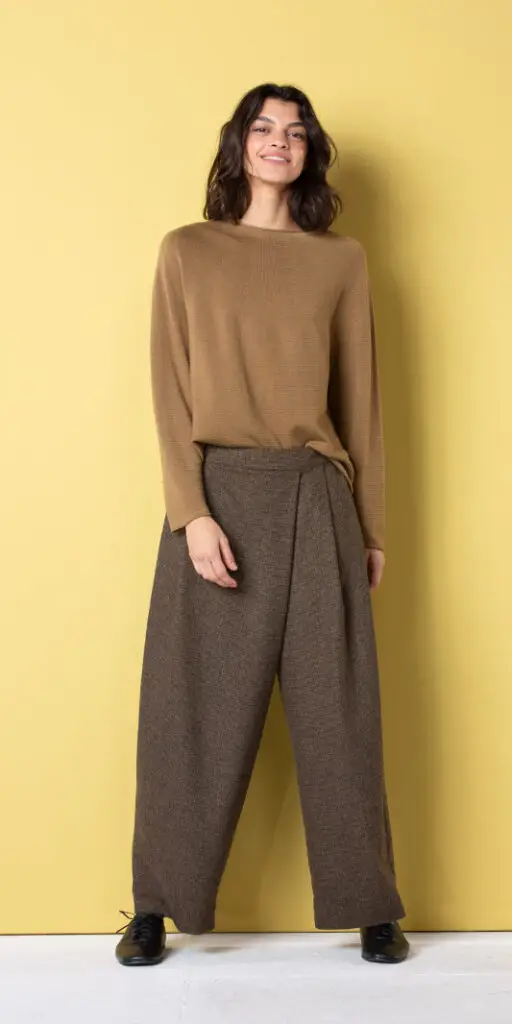 Model wearing stylish brown outfit against yellow background.