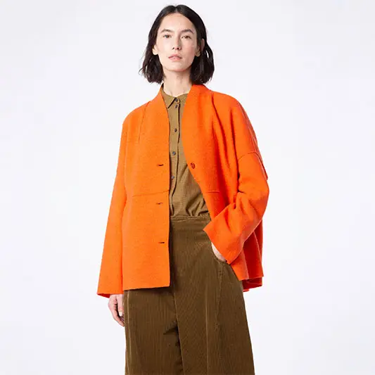 Model wearing an orange jacket and brown pants.