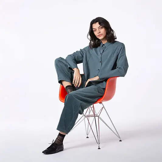 Woman in stylish outfit sitting on chair.