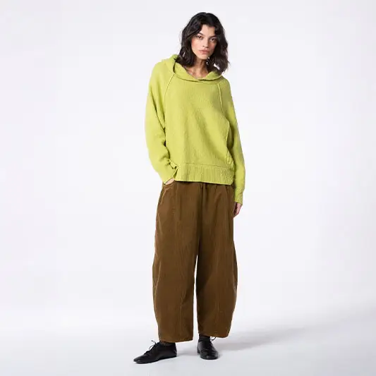 Woman wearing green sweater and brown pants.
