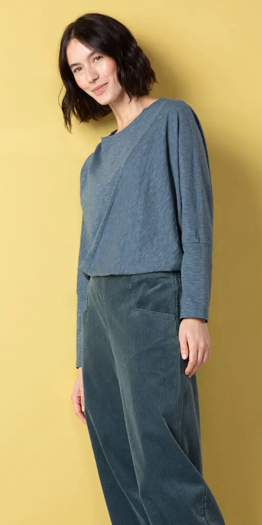 Woman in stylish blue outfit against yellow background.