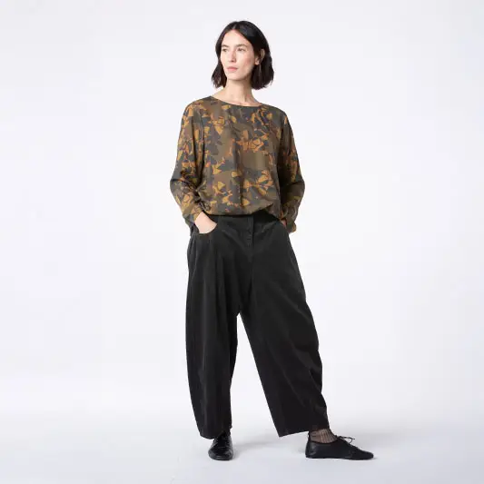Model wearing a patterned shirt and black pants.