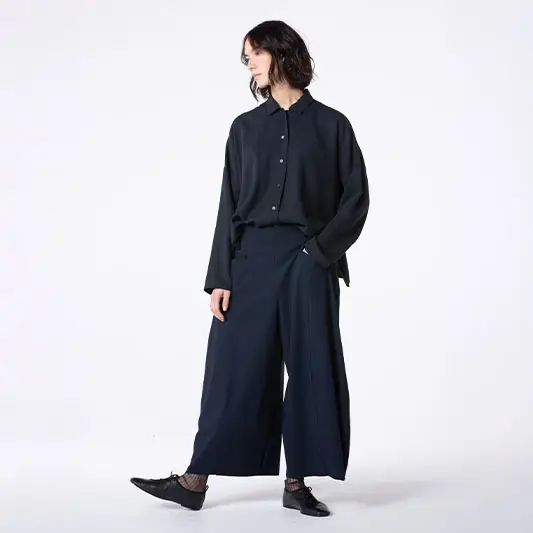 Fashion model wearing black shirt and wide pants.