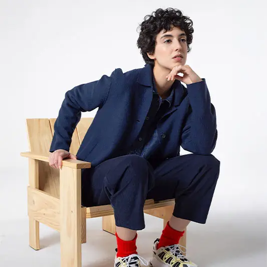 Person in stylish outfit sitting on chair.