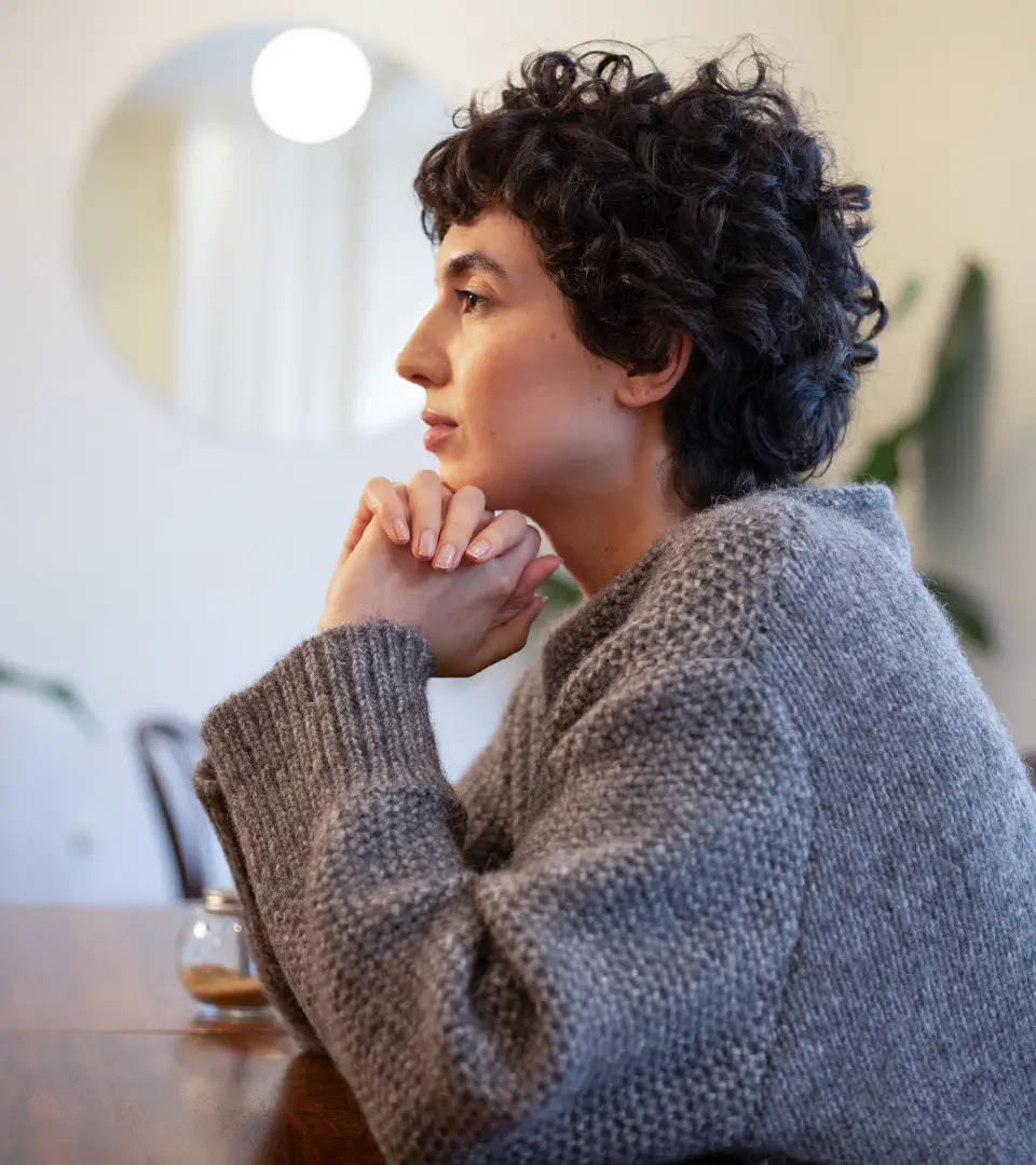Thoughtful person in cozy sweater at home