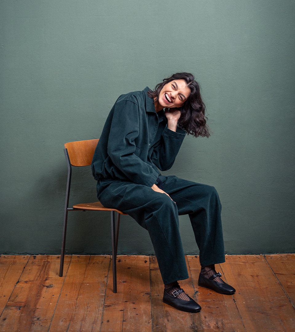 Smiling woman in stylish jumpsuit sitting.