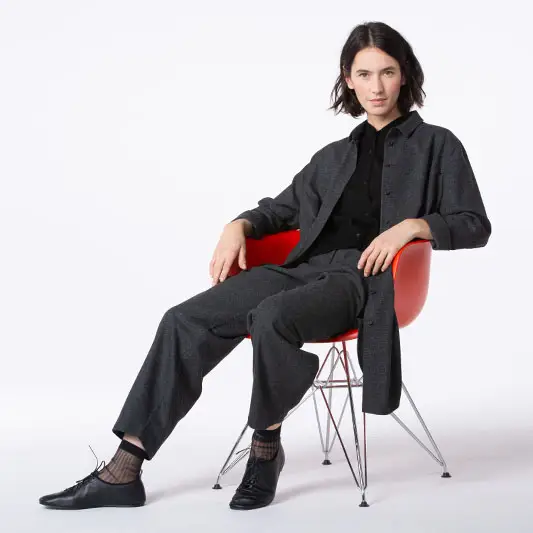 Person in gray outfit sitting on red chair.