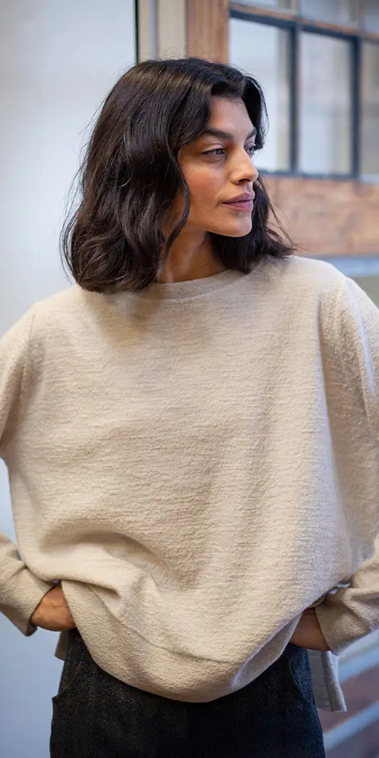 Femme en pull beige, regardant sur le côté.