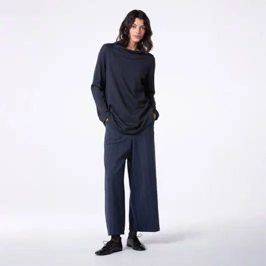 Woman wearing a dark top and wide trousers.