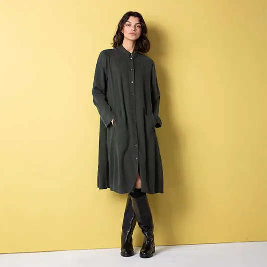 Woman in long green dress against yellow background.