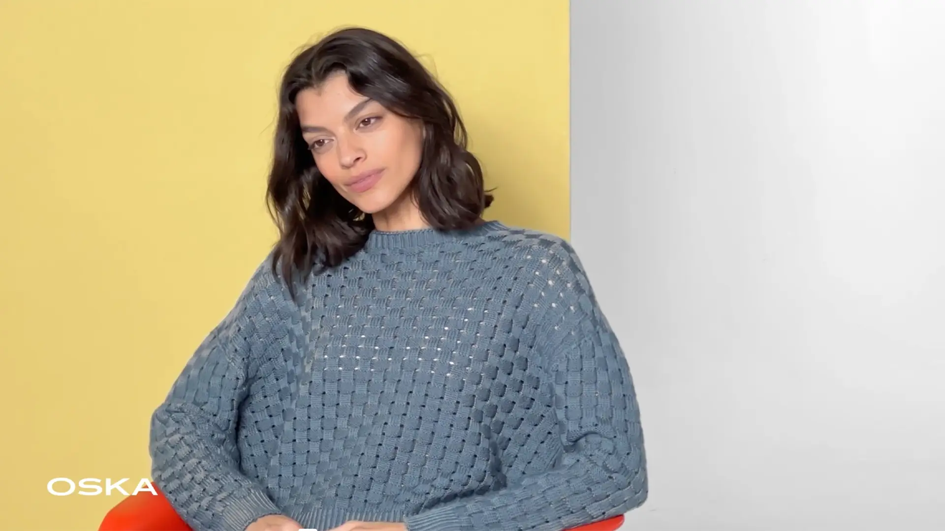 Woman in blue sweater against yellow background.