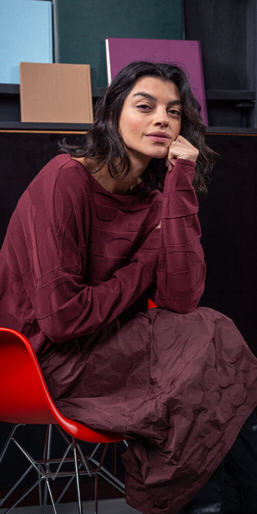 Woman sitting in a red chair, thoughtful pose.