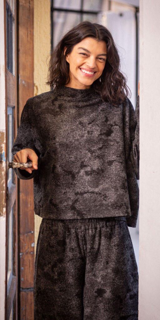 Smiling person in casual gray outfit at doorway.