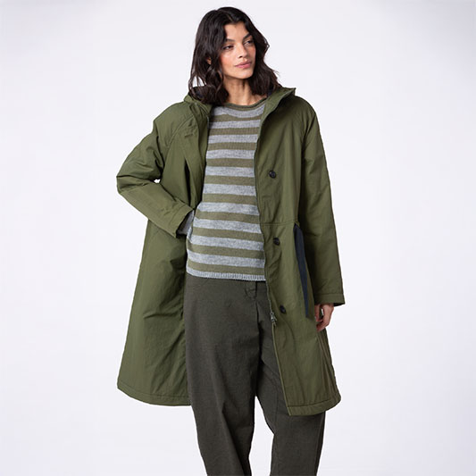 Model wearing a green coat and striped sweater.