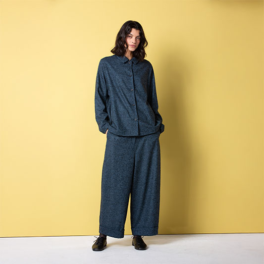 Model in dark outfit against yellow background.
