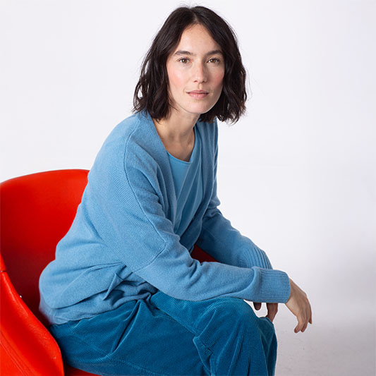 Woman in blue clothing sitting on a red chair.