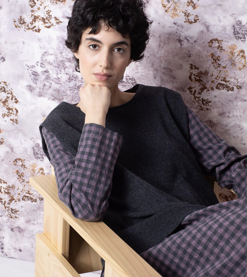 Person in stylish outfit seated thoughtfully.