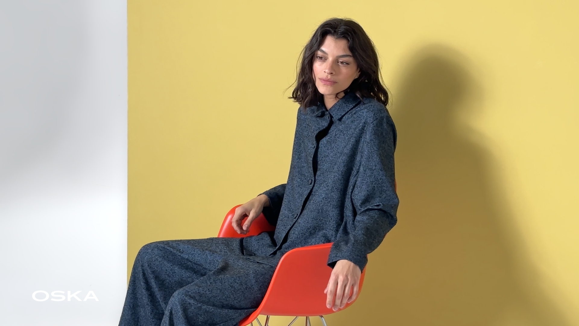 Woman in stylish outfit, sitting on chair.