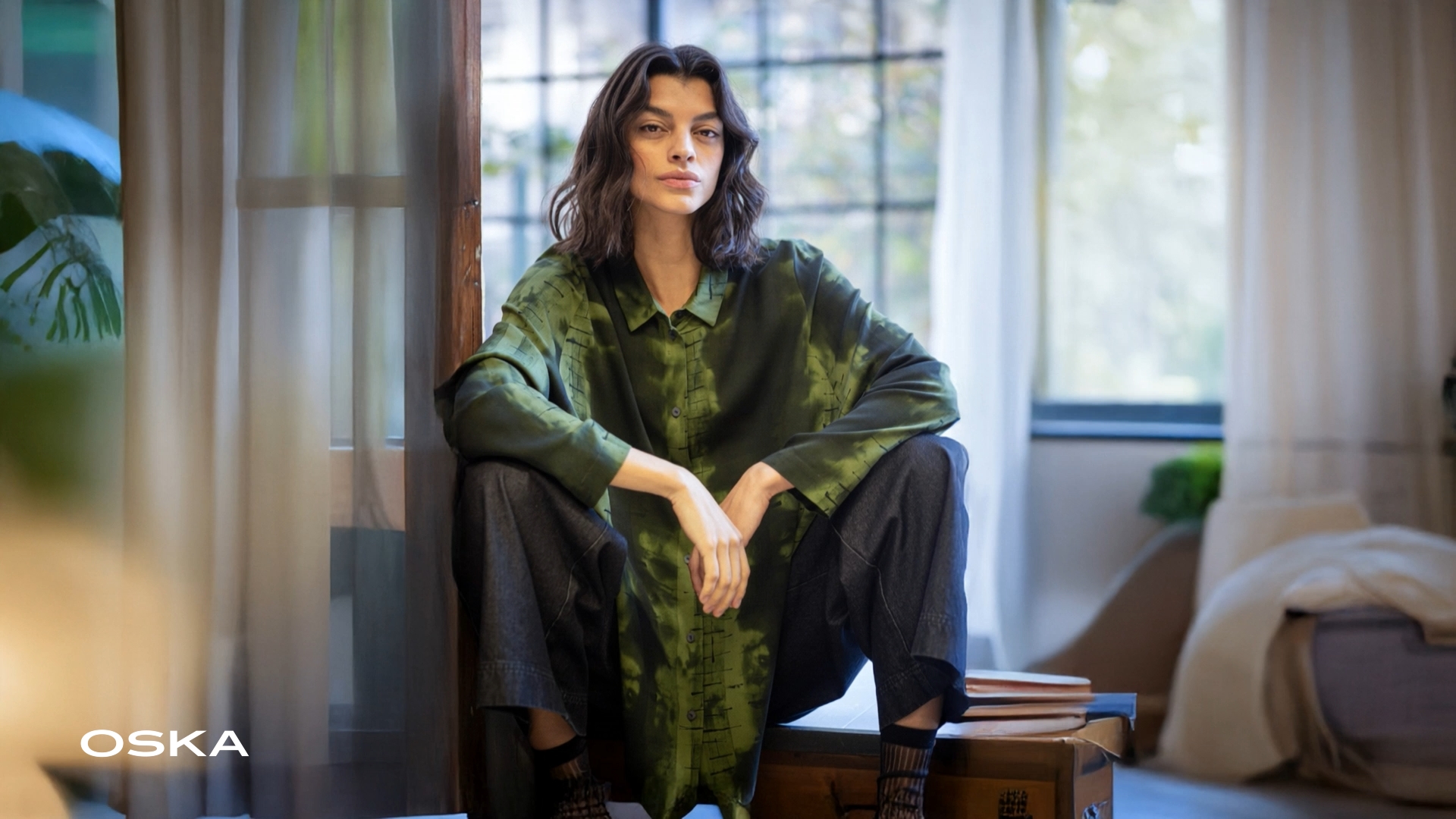 Model posing in stylish green outfit indoors.