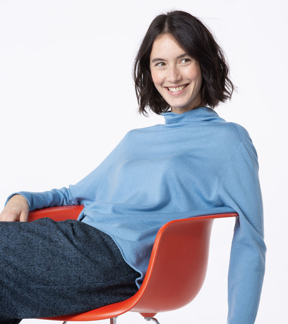 Smiling woman wearing a blue top, seated.