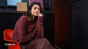 Woman in stylish maroon outfit sitting on chair.