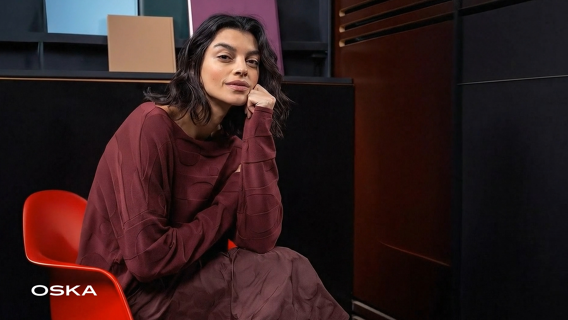 Woman in stylish maroon outfit sitting on chair.