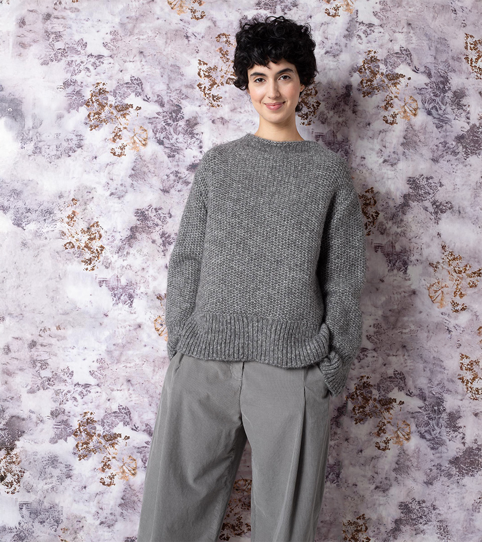 Smiling woman in gray sweater and pants.