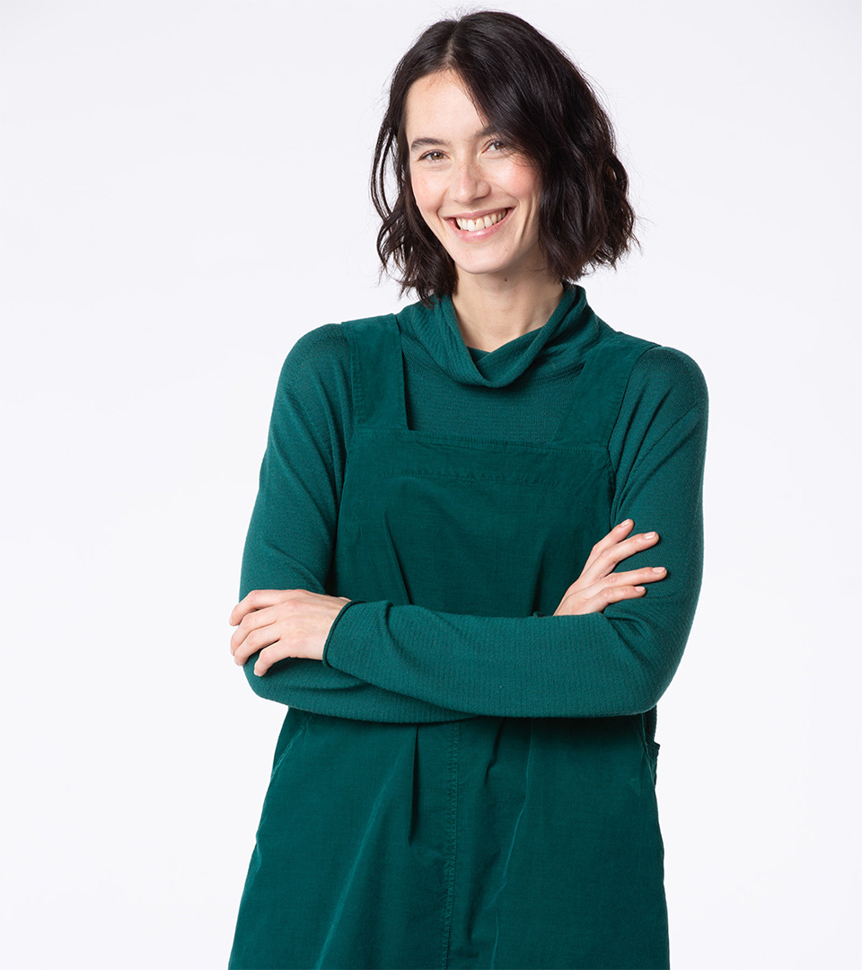 Smiling woman in green outfit with crossed arms.