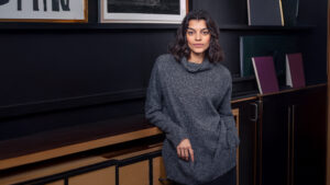 Woman in cozy sweater against dark background.