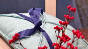 Blue cushion with a blue ribbon and berries.