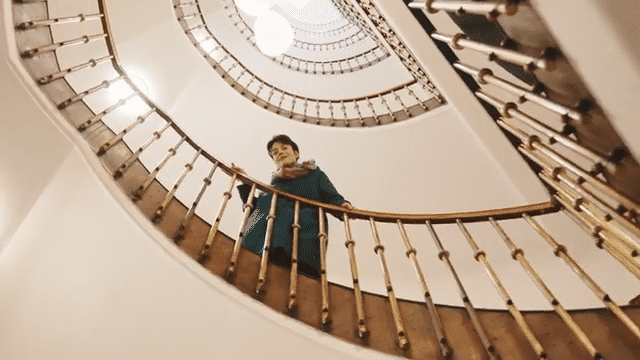 Woman on a spiral staircase looking down.