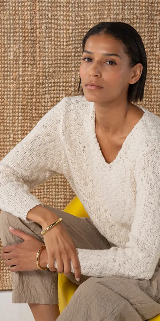 Person wearing a light sweater and accessories.