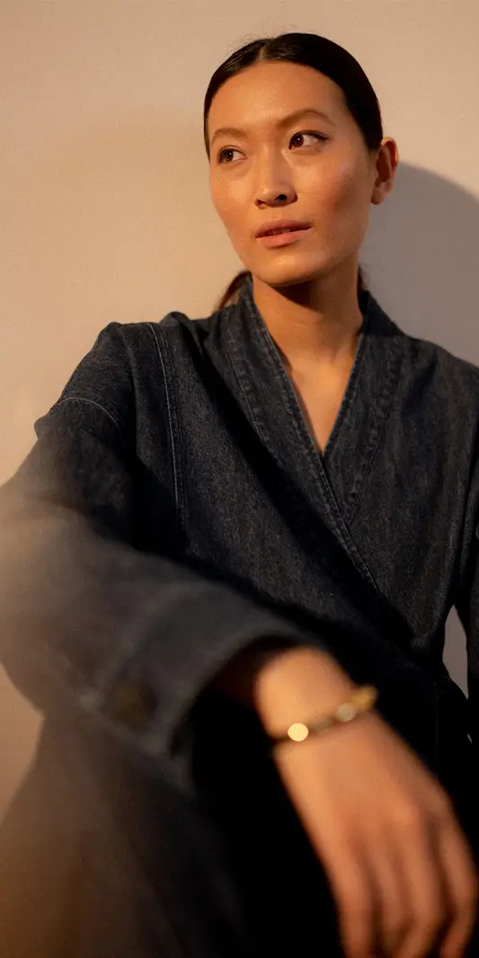 Femme en tenue en jean, expression pensive.