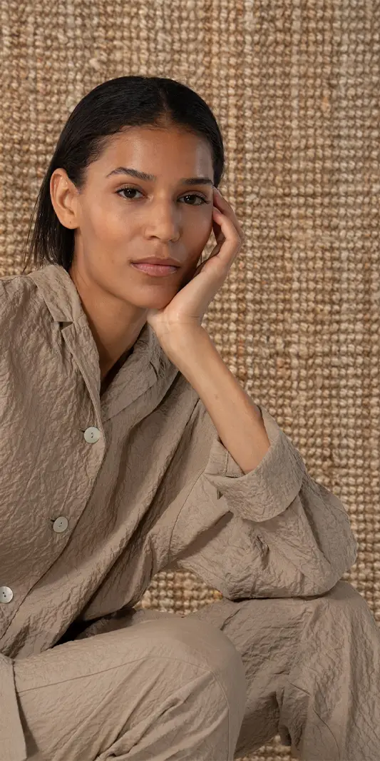 Femme vêtue de vêtements neutres, expression pensive.