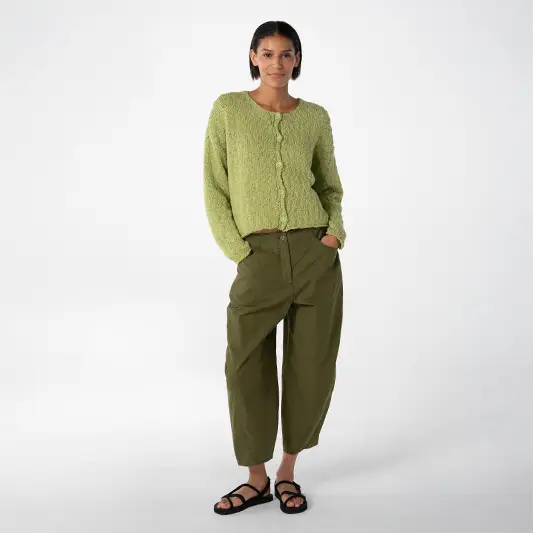 Woman wearing a green sweater and pants.