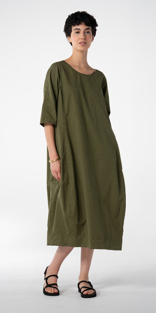 Woman in a green oversized dress and sandals.