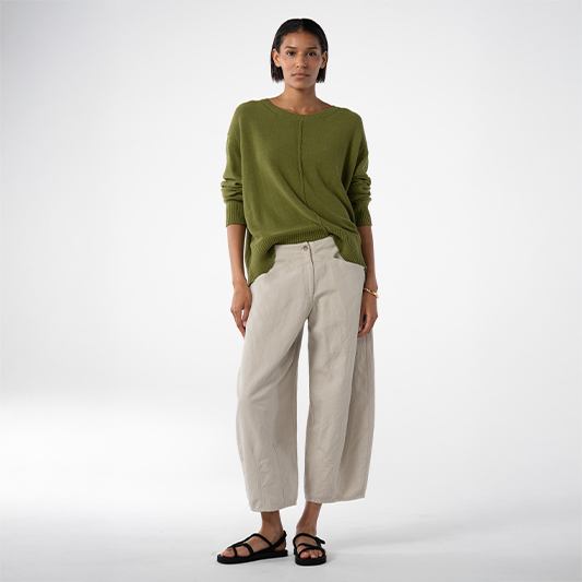 Woman wearing green sweater and light pants.